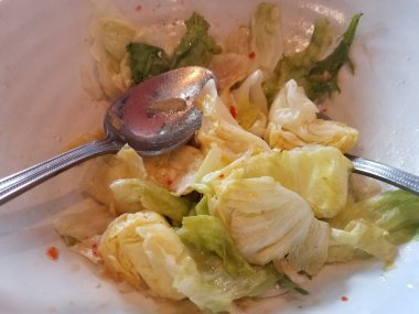 Sos ve kaşıklarla salatalı beyaz bir kase.