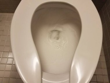 Banyoda sifonu çekilen beyaz tuvalet.
