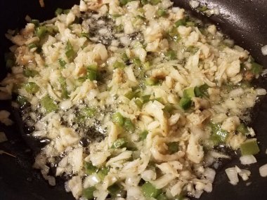 Kızartma tavasında morina, yeşil biber ve soğan ve yağ.