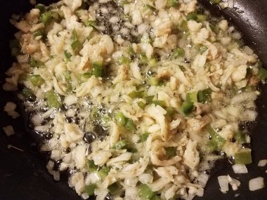 Kızartma tavasında morina, yeşil biber ve soğan ve yağ.