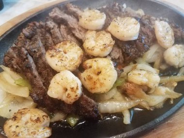 Biftek ve karides fajitası, soğan ve biber.