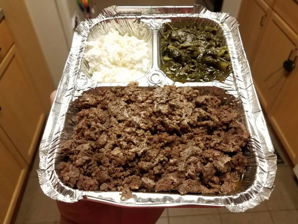 キッチンの金属トレイにエチオピア料理の牛肉と緑とチーズを手に — ストック写真