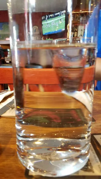满是水的桌子上的杯子和折射或变形 — 图库照片