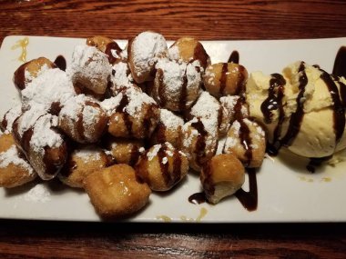 Pudra şekerli kızarmış hamur ve çikolata şurubu ve vanilyalı dondurma.