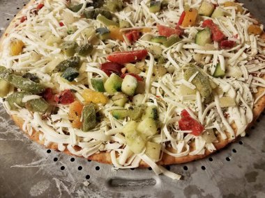 Metal pişirme tepsisinde peynirli dondurulmuş sebzeli pizza.