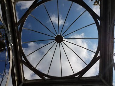 Dairesel metal yapı ve bulutlu mavi gökyüzü