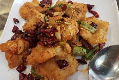 Kırmızı biberli baharatlı Çin balığı ve kaşıklı tabak.