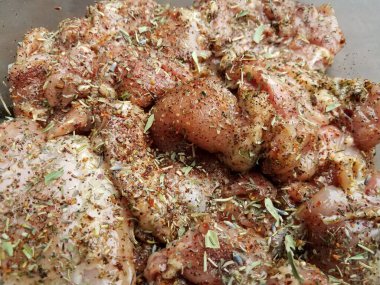 Baharat ve otlarla kaplı büyük çiğ tavuk parçaları.