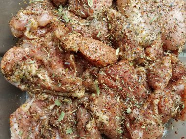 Baharat ve otlarla kaplı büyük çiğ tavuk parçaları.