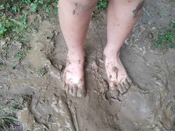 child\'s bare feet in dirty of filthy wet mud