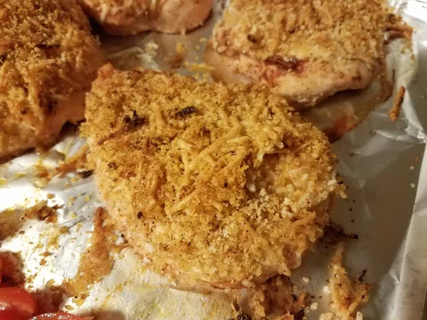 breaded chicken breasts with cheese on foil on baking tray