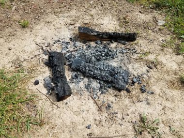 Yanmış kütükler ve yeşil çimlere atılmış siyah kömür kullanılmış.