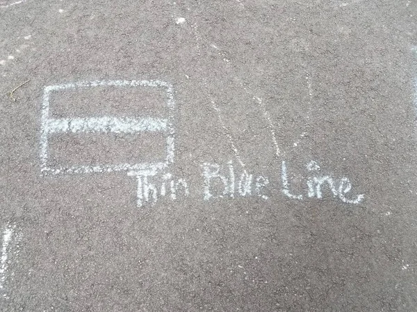 thin blue line art using blue chalk on black asphalt