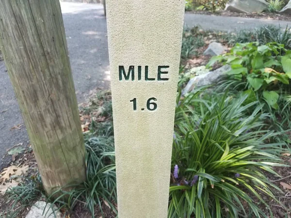 a grey cement mile 1.6 marker along a trail