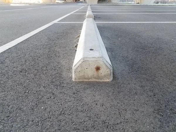 cement or concrete curb in parking lot with asphalt