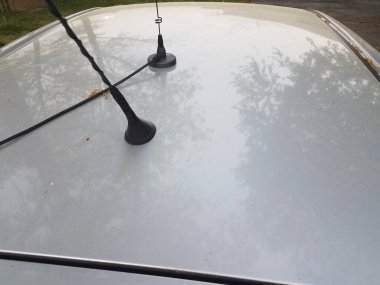 Çatısında iki anten olan gümüş ya da gri bir araba.