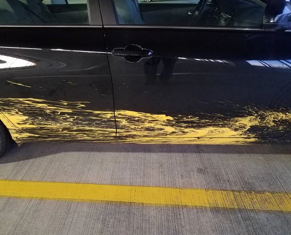 黄色の塗装スプラッタと黄色のラインでセメントと黒の車 — ストック写真