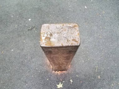 Siyah asfalt yolda suyla birlikte kahverengi metal çubuk veya kalın kazık.