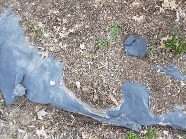 kahverengi saman ve açığa çıkmış siyah plastik peyzaj kumaşı ve yabani otlar