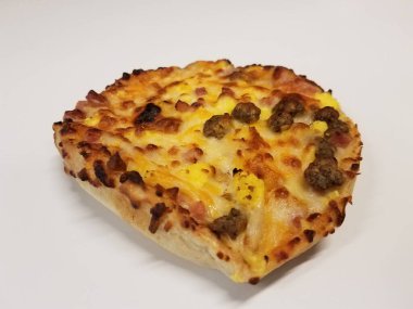 Kahvaltı pizzası, yumurta, sosis ve pastırma beyaz masada.