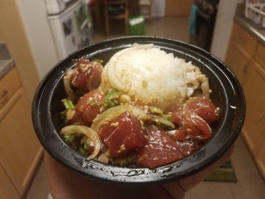 Mutfakta bir kase çiğ ton balığı, pirinç ve soğan var.