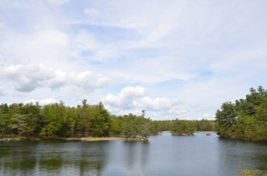 Kanada 'da göl ya da nehir suyu ve ağaçlar ve bulutlar Birleşik Devletler sınırında