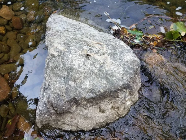large grey rock or boulder in a small stream