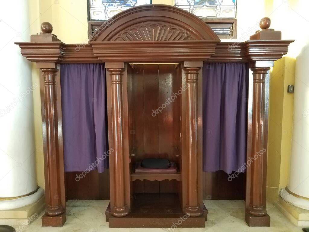 wooden confession booth with cushion and purple curtain or fabric