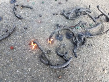 Kara asfaltta bir sürü kömür yılanı havai fişeği var.