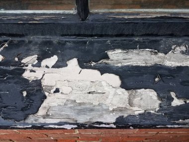 Eski bir ahşap pencere pervazından dökülen siyah boya.