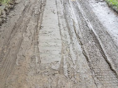 Kalın çamurda bir sürü bisiklet, araba ve ayakkabı izi var.