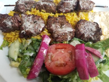 Soslu biftek, pilav, domates ve salata.