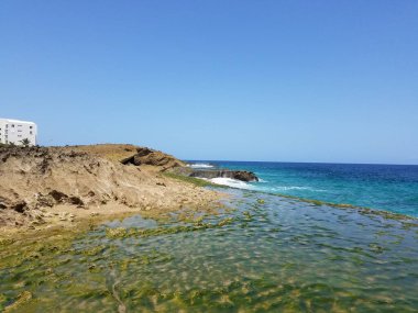 Porto Riko 'da bir sahilde kayalar, kum ve dalgalar.