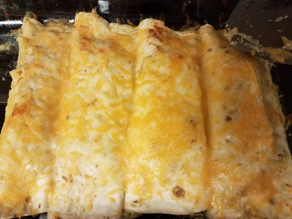 Enchiladas sajtot üveg serpenyőben tűzhelyen spatulával — Stock Fotó