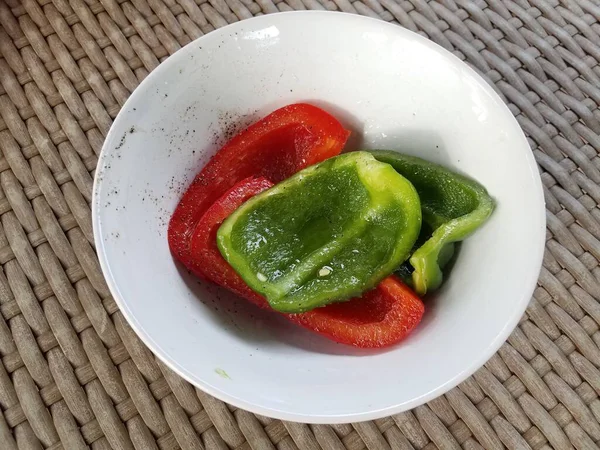 Tigela com pimentas verdes e vermelhas temperadas na mesa — Fotografia de Stock