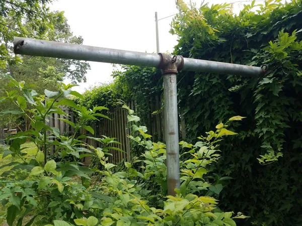 Logam clothesline tiang dengan tanaman hijau dan pagar — Stok Foto