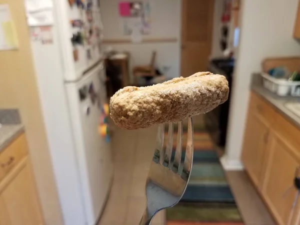 Viande de saucisse congelée sur une fourchette dans la cuisine — Photo