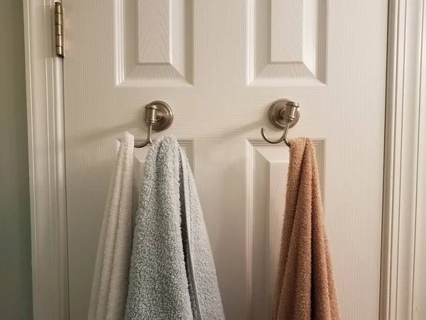 Havlular beyaz banyo kapısında asılı.