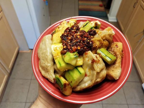 Hand houden kom van Chinese komkommer en dumplings met hete chilis — Stockfoto