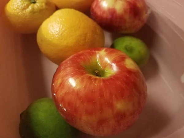 Manzanas y naranjas y limas flotando en el agua — Foto de Stock