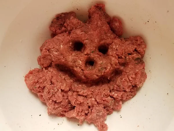 Лицо с улыбкой и глазами в сырой свинине в контейнере — стоковое фото