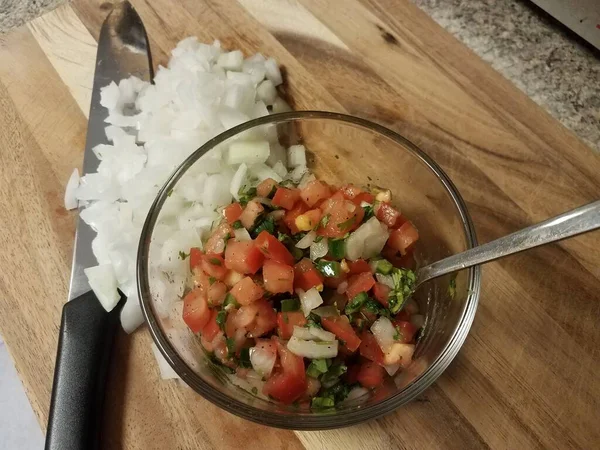 Tomates et oignons et bol en verre sur planche à découper — Photo