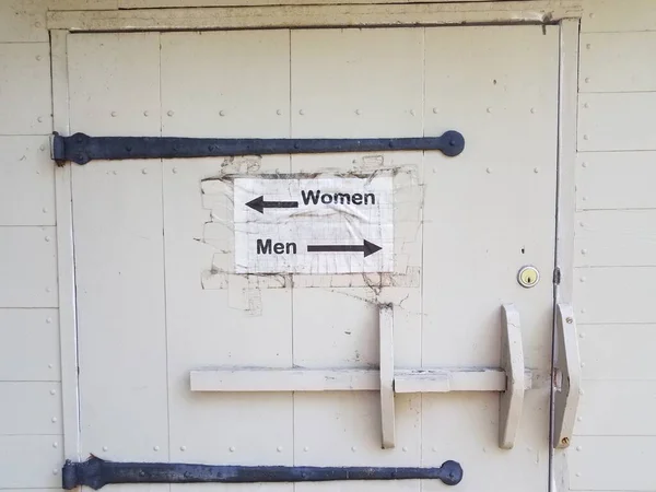 Puerta de madera con hombres y mujeres letrero de baño y flechas — Foto de Stock