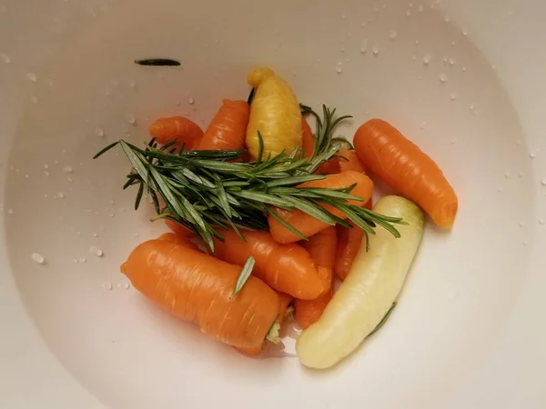 Zanahorias y romero en un recipiente o recipiente blanco — Foto de Stock