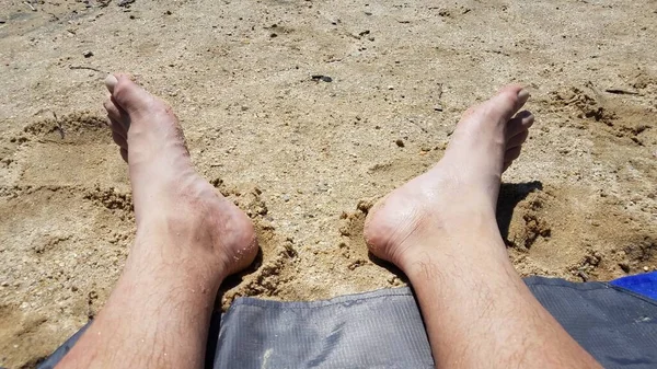 Pés masculinos na areia e seixos na praia — Fotografia de Stock