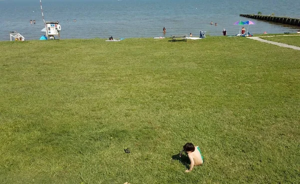 Fiú gyermek ül a füvön a strandon — Stock Fotó