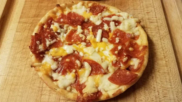 Small pepperoni and cheese pizza on cutting board — Stock Photo, Image