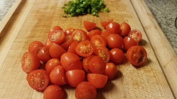 Tomates vermelhos na tábua de corte com cebolinha — Fotografia de Stock