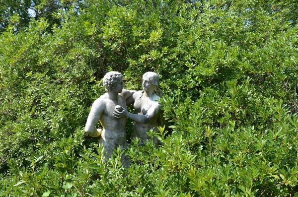 Adam und Eva Statue mit Apfel und grünen Pflanzen — Stockfoto