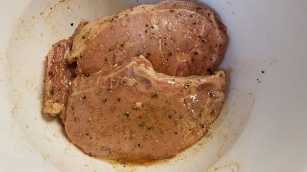 Costeletas de porco temperadas com óleo em recipiente branco — Fotografia de Stock